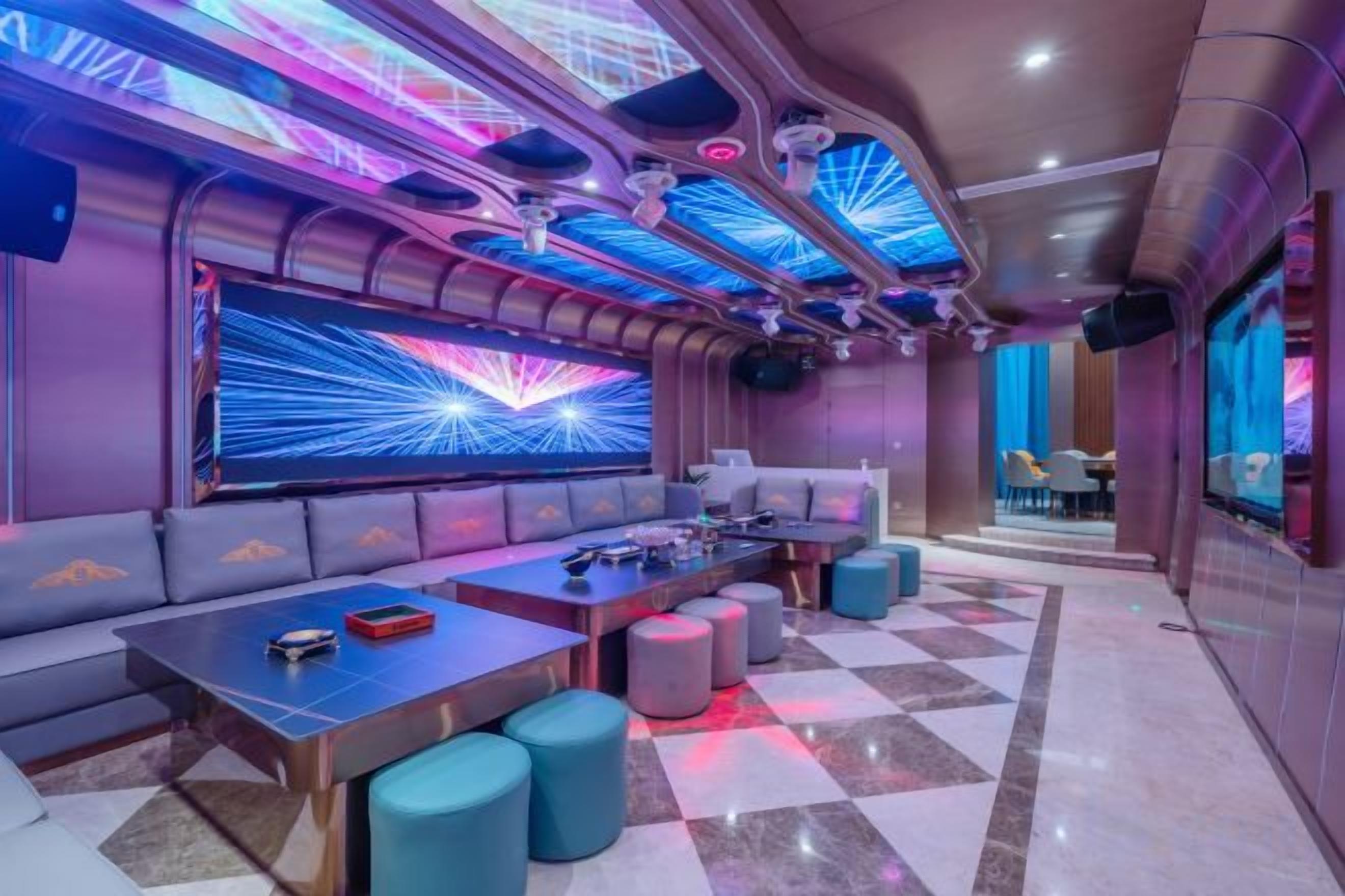 A modern lounge area with seating, tables, and a large screen.