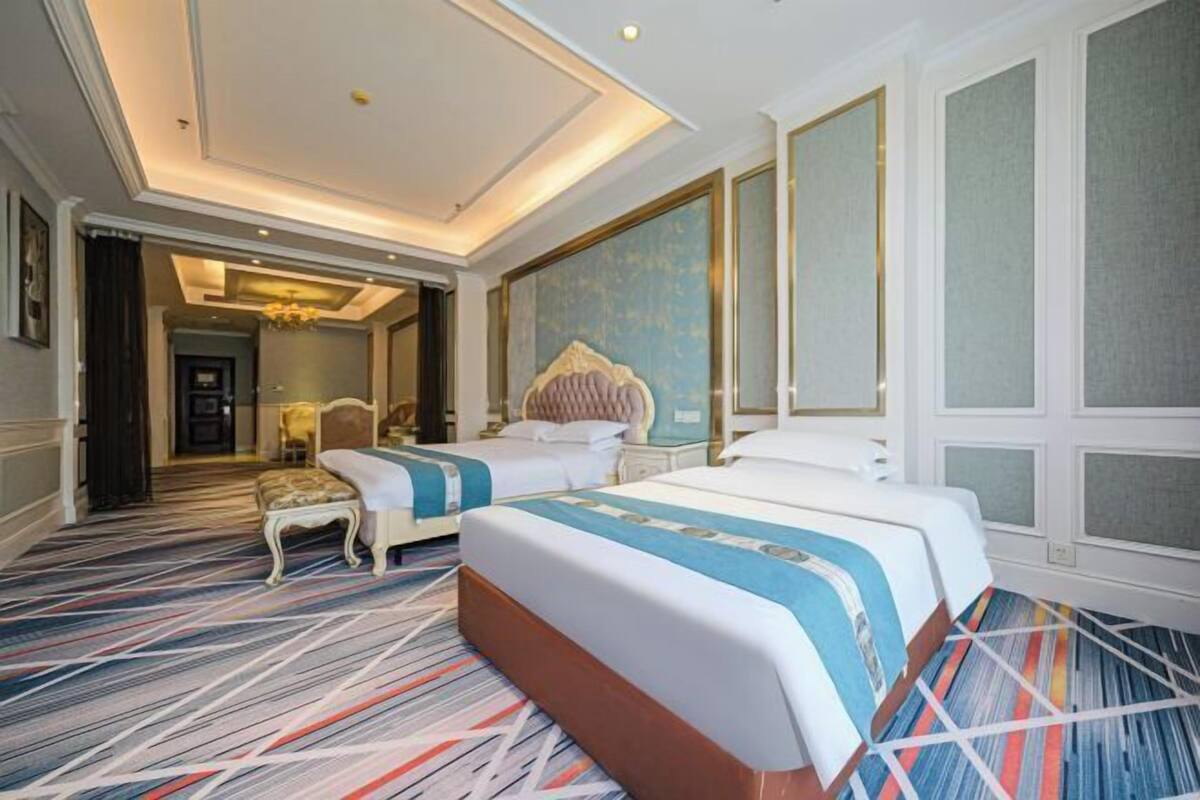 Une chambre d’hôtel avec un grand lit, un petit coin salon et une vue sur le couloir.