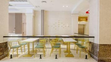 Un vestíbulo de hotel con suelo de mármol, barandilla de cristal y una fila de mesas y sillas.