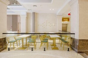 Un vestíbulo de hotel con suelo de mármol, barandilla de cristal y una fila de mesas y sillas.