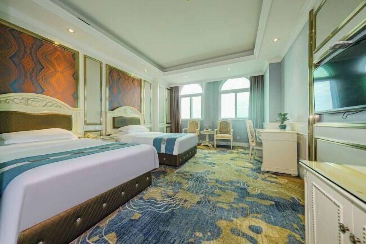 Une chambre d’hôtel avec deux lits, un bureau, une chaise et un téléviseur.