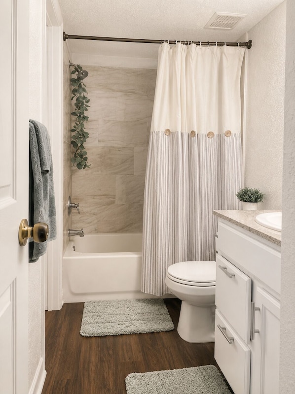 A bathroom with a bathtub, toilet, and vanity.
