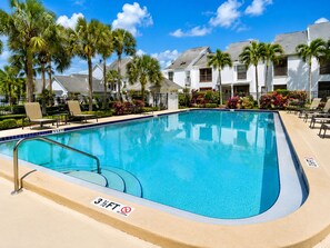 A swimming pool with a 3 1/2 ft depth marker, surrounded by lounge chairs and palm trees.