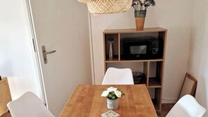 A wooden dining table with white chairs, a vase with flowers, and a small decorative item on the table. - Gemütliche Ferienwohnung im Bergischen - Nähe Köln/bonn Haustierfreundlich! (Much)