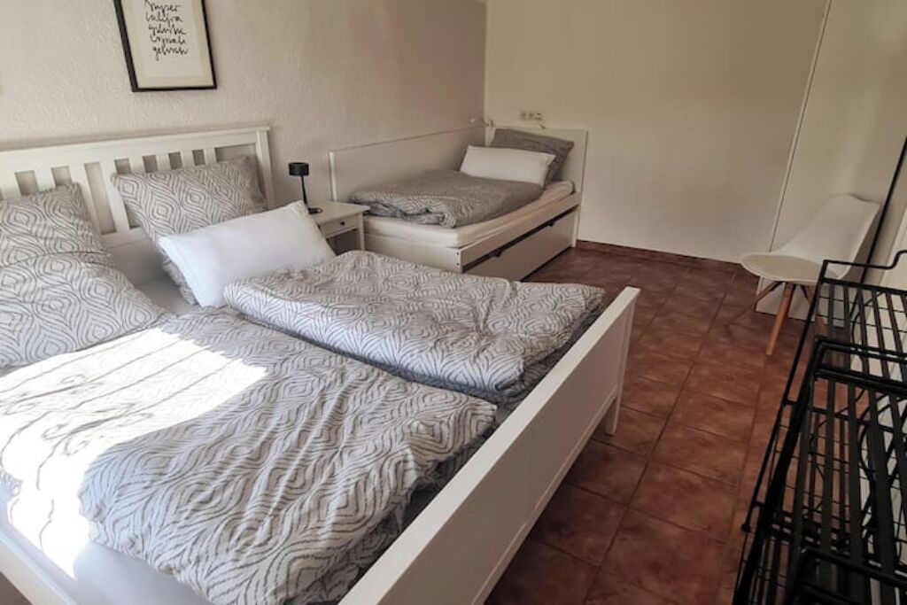 Ein Schlafzimmer mit zwei Betten, einem Nachttisch, einem Sessel und einem gerahmten Bild an der Wand.