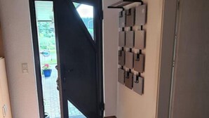 A hallway with a sliding glass door leading to an outdoor area, a tiled floor, and a wall-mounted light fixture. - Gemütliche Ferienwohnung im Bergischen - Nähe Köln/bonn Haustierfreundlich! (Much)