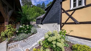 Una casa tradicional con entramado de madera y madera, con un sendero de piedra que conduce a la entrada, rodeada de jardines y árboles bien cuidados.