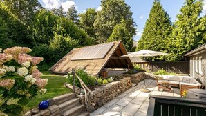 Un patio trasero con una escalera de piedra, una terraza de madera y un área de patio con mobiliario exterior.