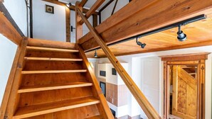 Una escalera de madera con barandilla que lleva a una habitación con puerta de madera y ventilador de techo.