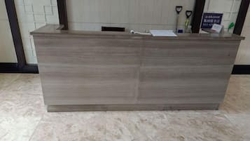 Un mostrador de recepción con superficie plana y un tirador, ubicado en una habitación con piso de baldosas.