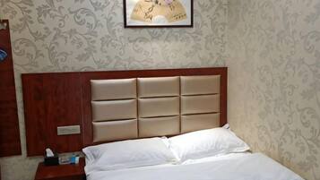 Una habitación de hotel con una cama, una mesita de noche y un cuadro en la pared.