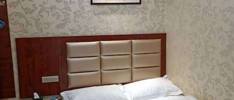 Una camera d'albergo con un letto, un comodino e un quadro appeso al muro.