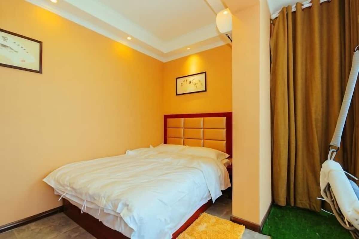 A hotel room with a bed, a headboard, a wall-mounted picture, and a curtain.