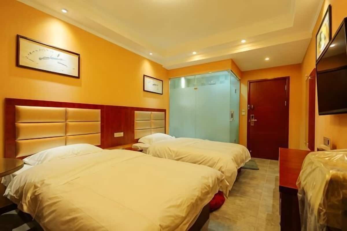 A hotel room with two beds, a wooden headboard, a television, and a door leading to a bathroom.