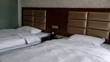 Habitación de hotel con dos camas, cabecera de madera y mesita de noche con lámpara.