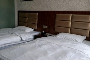 A hotel room with two beds, a wooden headboard, and a nightstand with a lamp. - Zhengzhou Wanyinli Hotel (Zhengzhou)
