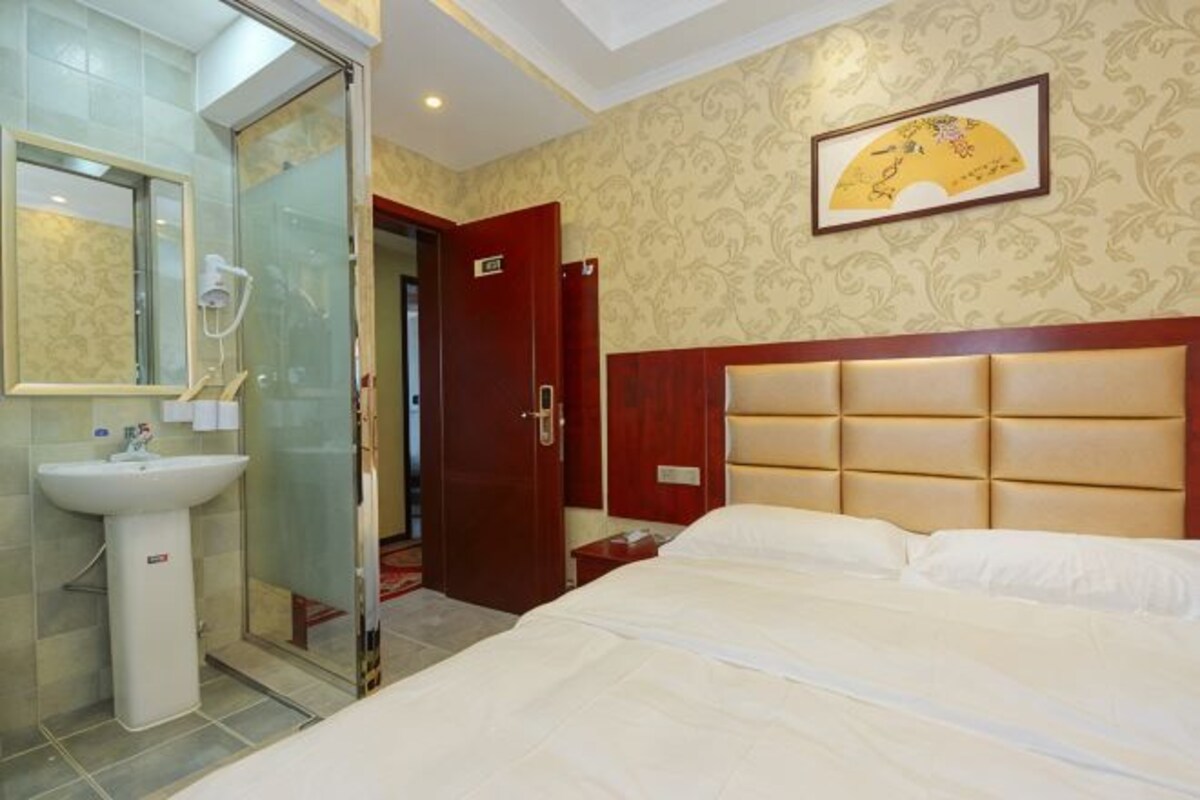 Quarto de hotel com cama, banheiro com pia e chuveiro.