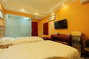 Quarto de hotel com duas camas, televisão, espelho, escrivaninha e frigorífico.