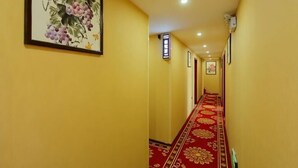 A hallway with yellow walls, a red carpet, and framed artwork on the walls. - Zhengzhou Wanyinli Hotel (Zhengzhou)