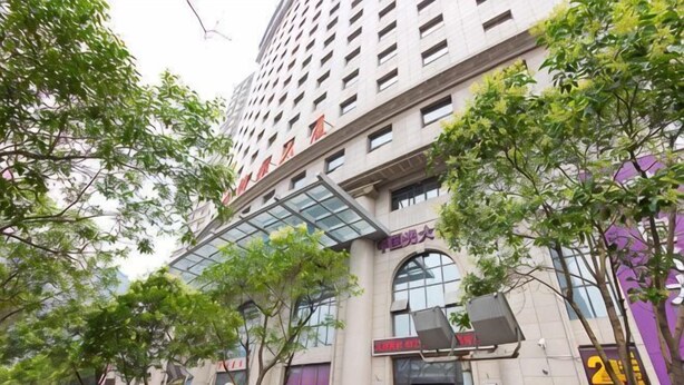 A multi-story building with a glass entrance, surrounded by trees. - Zhengzhou Wanyinli Hotel (Zhengzhou)