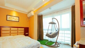 A hotel room with a bed, a hanging chair, a window with curtains, and a view of the outside. - Zhengzhou Wanyinli Hotel (Zhengzhou)