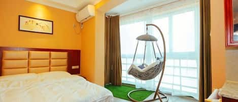 Habitación de hotel con cama, una silla colgante, una ventana con cortinas y vistas al exterior.