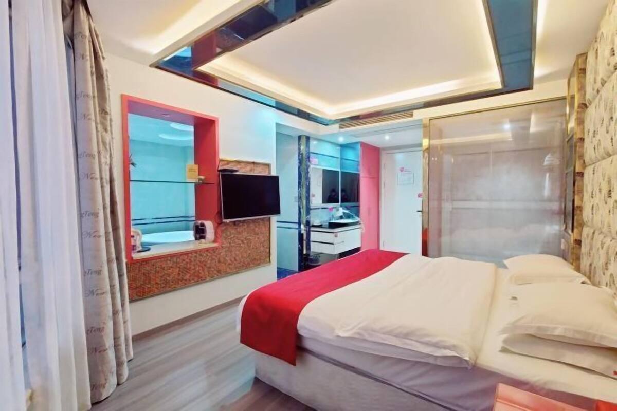 Une chambre d’hôtel avec un lit, une télévision, un miroir et une armoire.