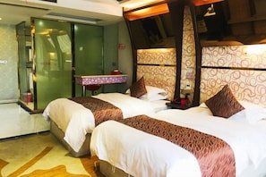 A hotel room with two beds, a small bedside table, a mirror, and a patterned wall.