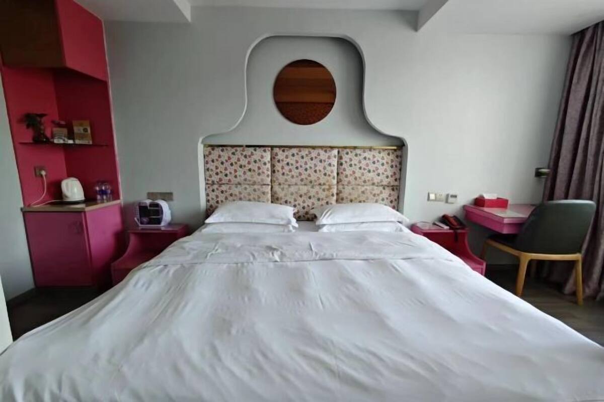 Une chambre d’hôtel comprenant un lit, un bureau, une chaise et une étagère fixée au mur.