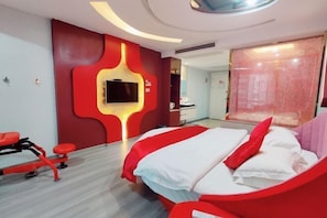 A modern hotel room with a bed, a TV mounted on the wall, and a red exercise bike.