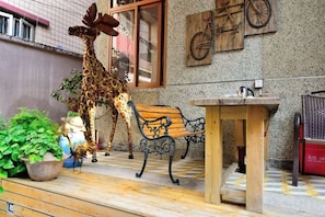 Quarto com uma estátua de girafa, um banco, uma mesa e uma bicicleta fixada na parede.