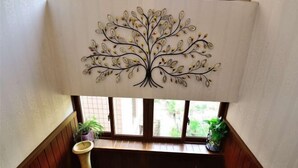 A room with a window, a decorative tree artwork on the wall, and a wooden bench. - Fuxing No. 10 Hotel (Xiamen)