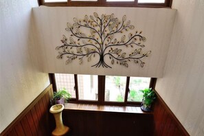 A room with a window, a decorative tree artwork, a wooden bench, and a potted plant. - Fuxing No. 10 Hotel (Xiamen)