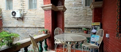 An outdoor patio with a stone wall, a round table, and metal chairs.