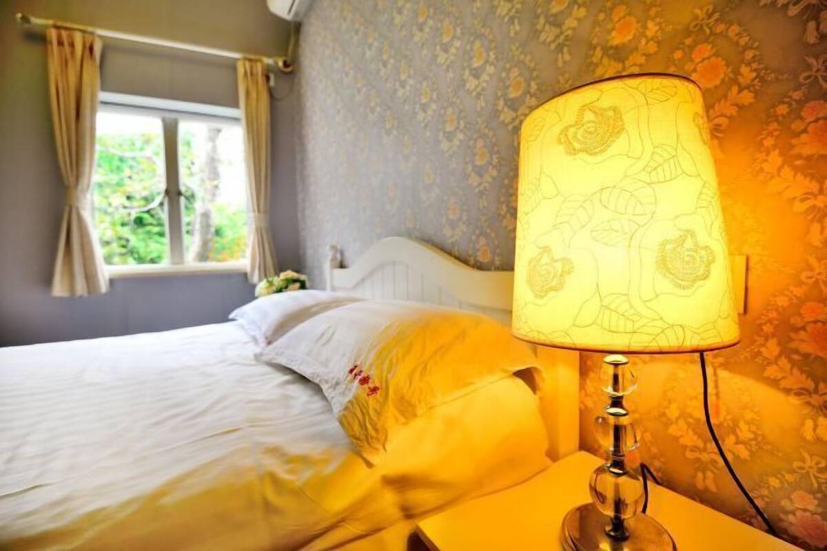 A bedroom with a bed, a nightstand, and a lamp.
