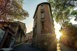 Uma rua estreita com um edifício alto de tijolos à direita.