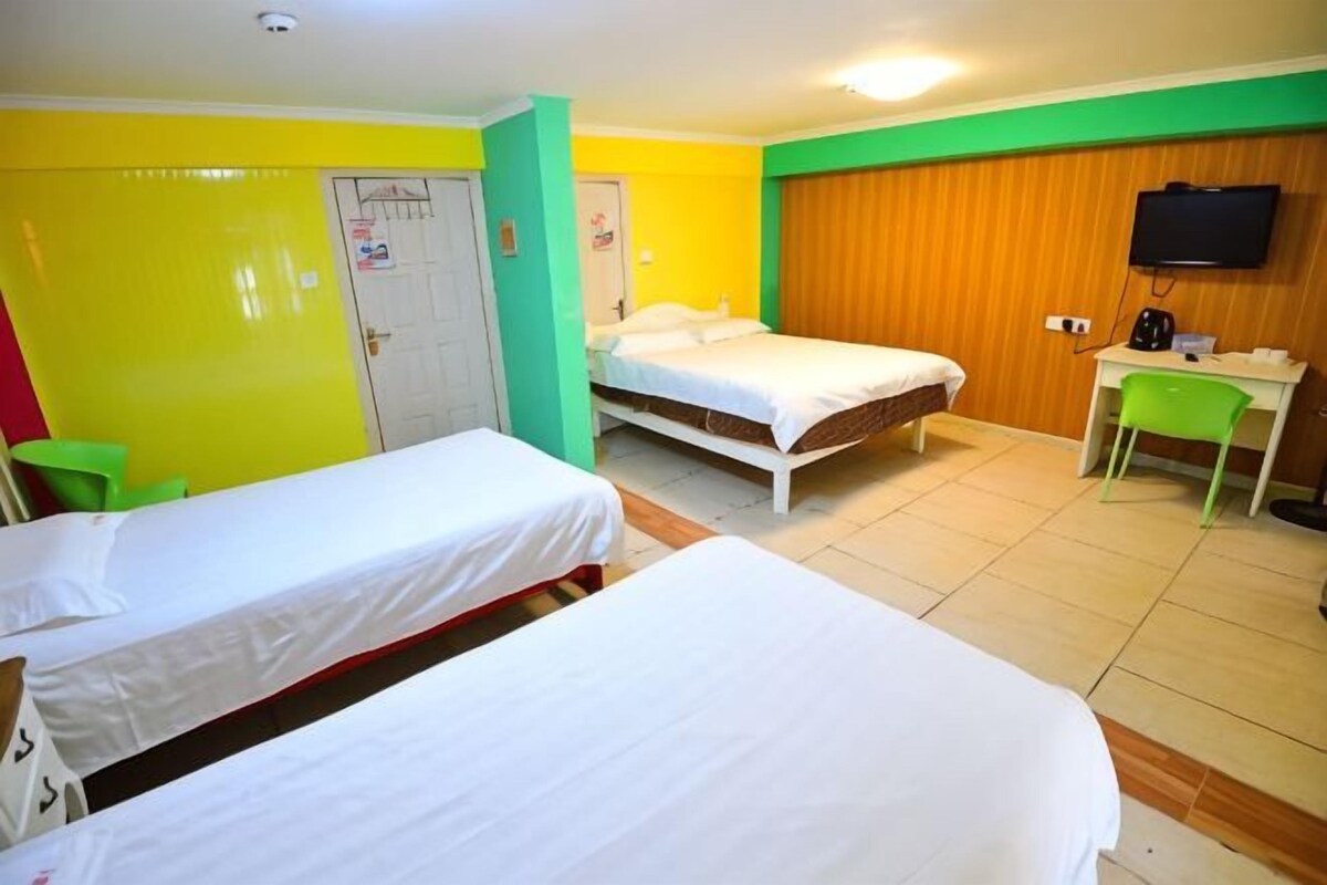 A hotel room with two beds, a desk, a chair, and a television.