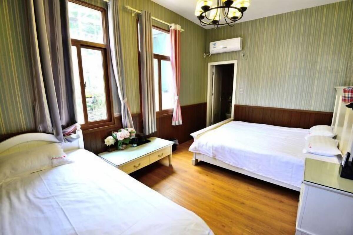 A hotel room with two beds, a desk, and a wardrobe.