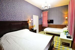 A hotel room with two beds, a television, a nightstand, a lamp, and a patterned floor. - Fuxing No. 10 Hotel (Xiamen)