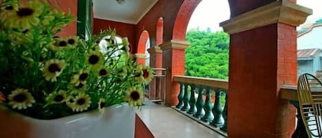 A corridor with a potted plant, brick arches, and a view of greenery.