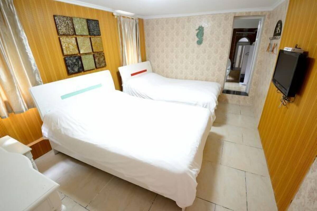 A hotel room with two beds, a small desk, a television, and a bathroom.