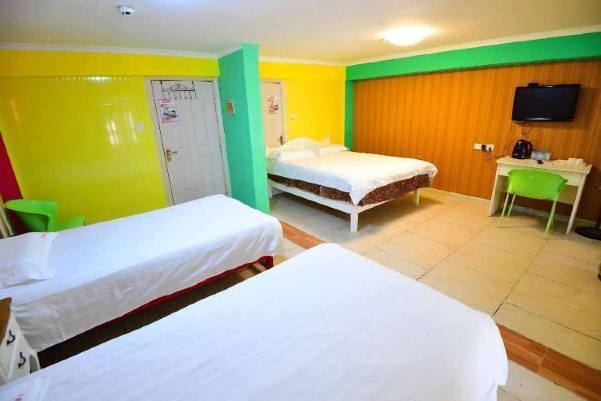 A hotel room with two beds, a desk, a chair, a television, and a door.