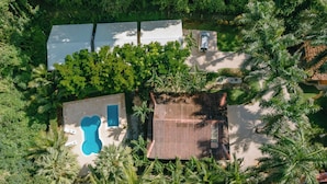 An aerial view of a resort with a swimming pool, a wooden deck, and dense tropical vegetation. - Serene Jungle Bungalow at Mística Natural, Just Minutes to Stunning Beaches! (Puerto Viejo)