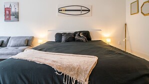 Makuuhuone, jossa on sänky, yöpöydät, lamppu, sohva ja seinätaideteos.