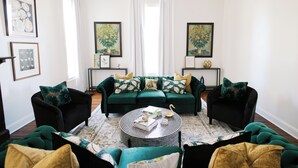 A living room with a green sofa set, a round coffee table, and artwork on the walls.