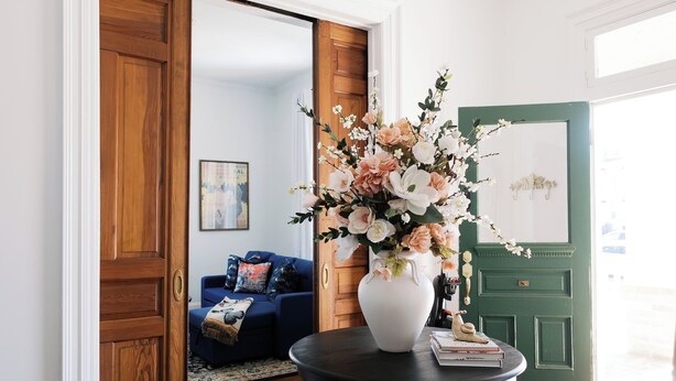 A room with a round table, a chandelier, a green door, and a blue sofa.