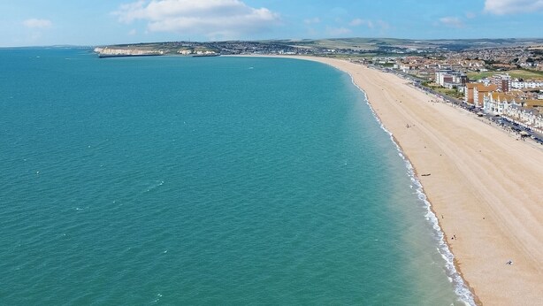 A coastal view with a sandy beach, a clear blue sky, and distant buildings. - Seaside Escape: Warm & Cosy Winter Getaway by the Sea (Seaford)