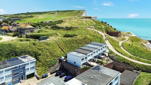 A coastal area with modern buildings, a golf course, and a cliff overlooking the sea. - Seaside Escape: Warm & Cosy Winter Getaway by the Sea (Seaford)