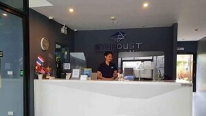 A reception desk with a logo, a clock, and a framed picture on the wall. - Stardust Boutique Hotel (Hua Hin)