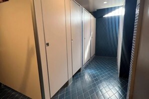 Un passadís amb terra de rajola, una porta i una finestra amb cortines.